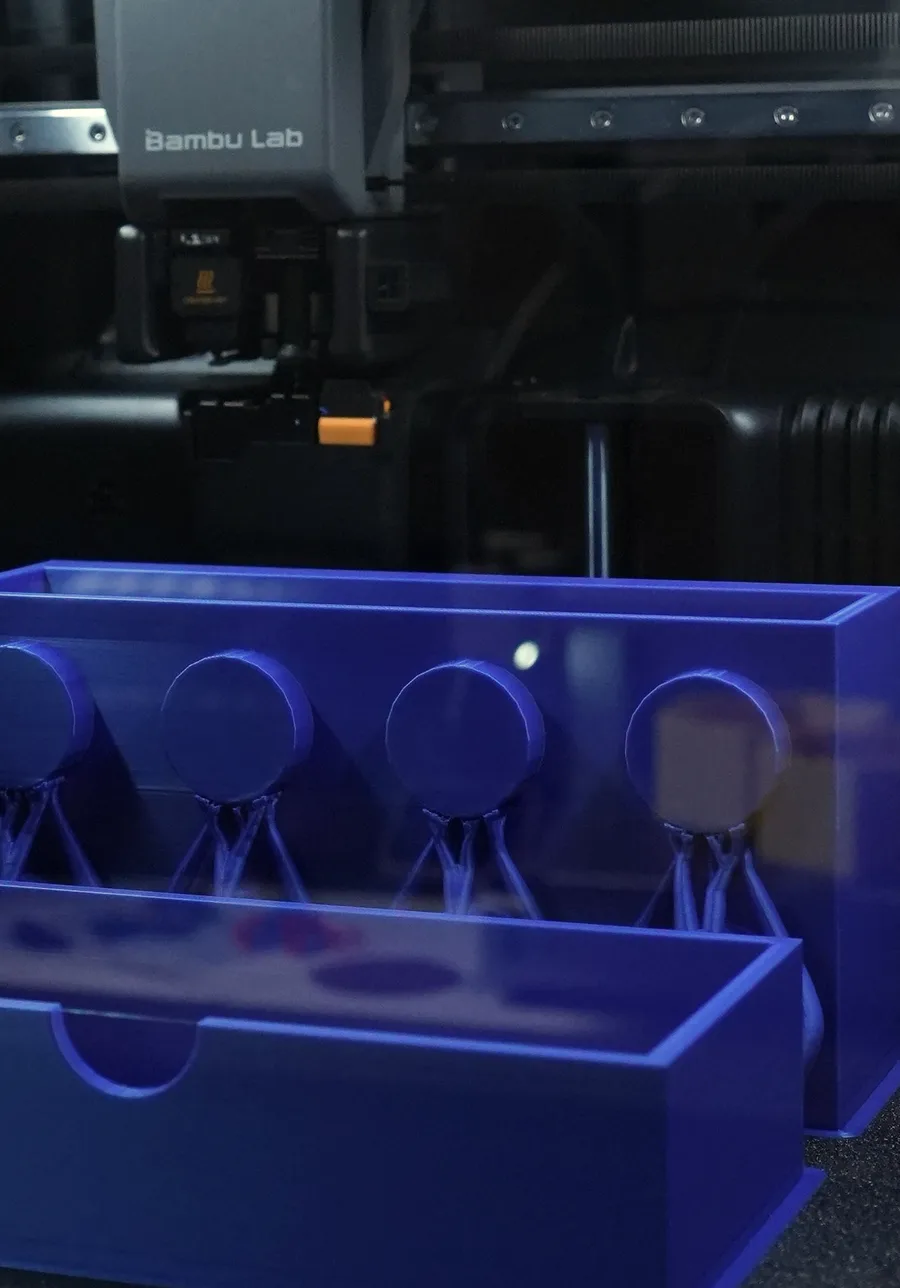 Two parts of one storage bin printed side by side on the plate, each circular tab standing on its own support column